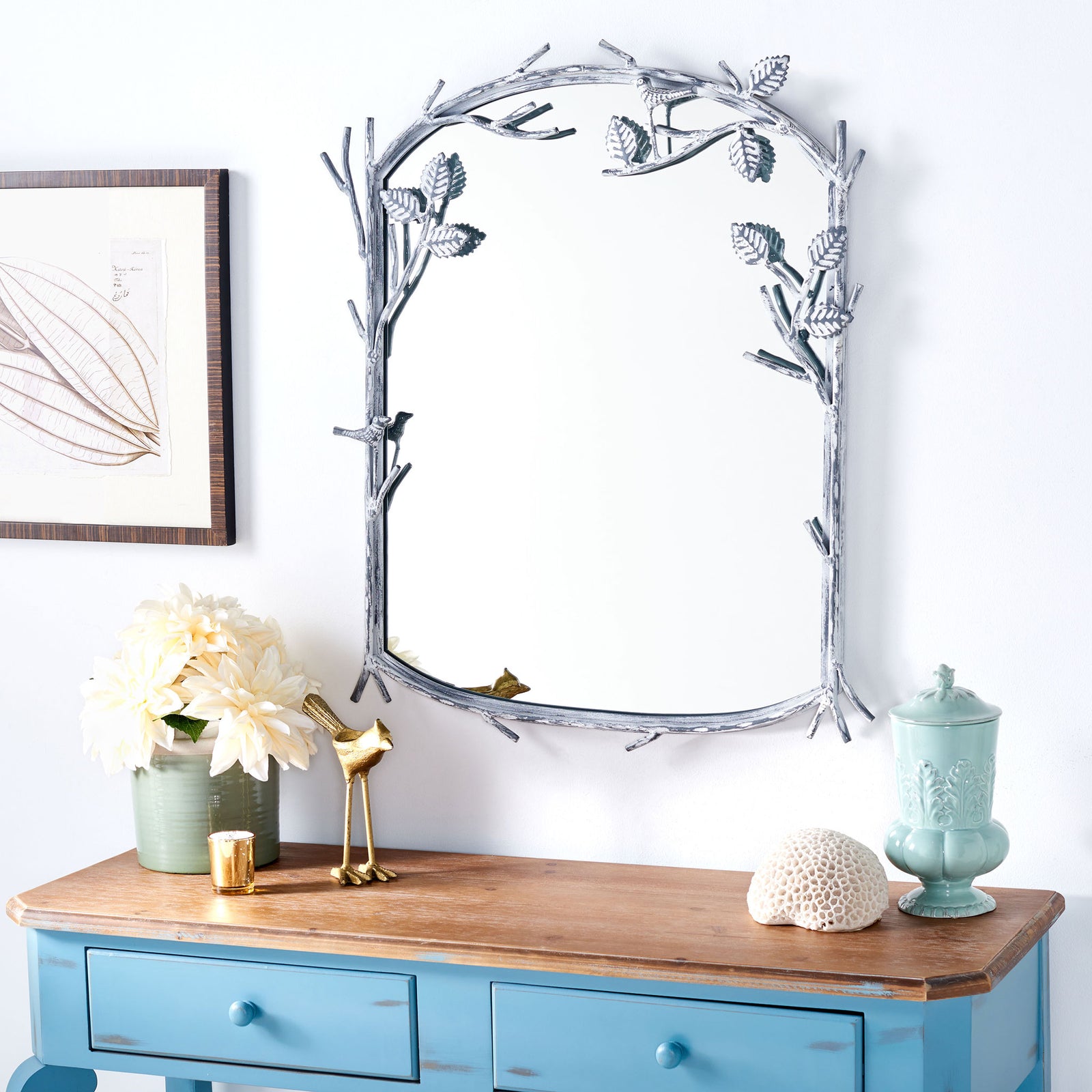 A silver mirror with sculpted branches brings a whimsical accent above a blue console. || MRR3042A || front_room