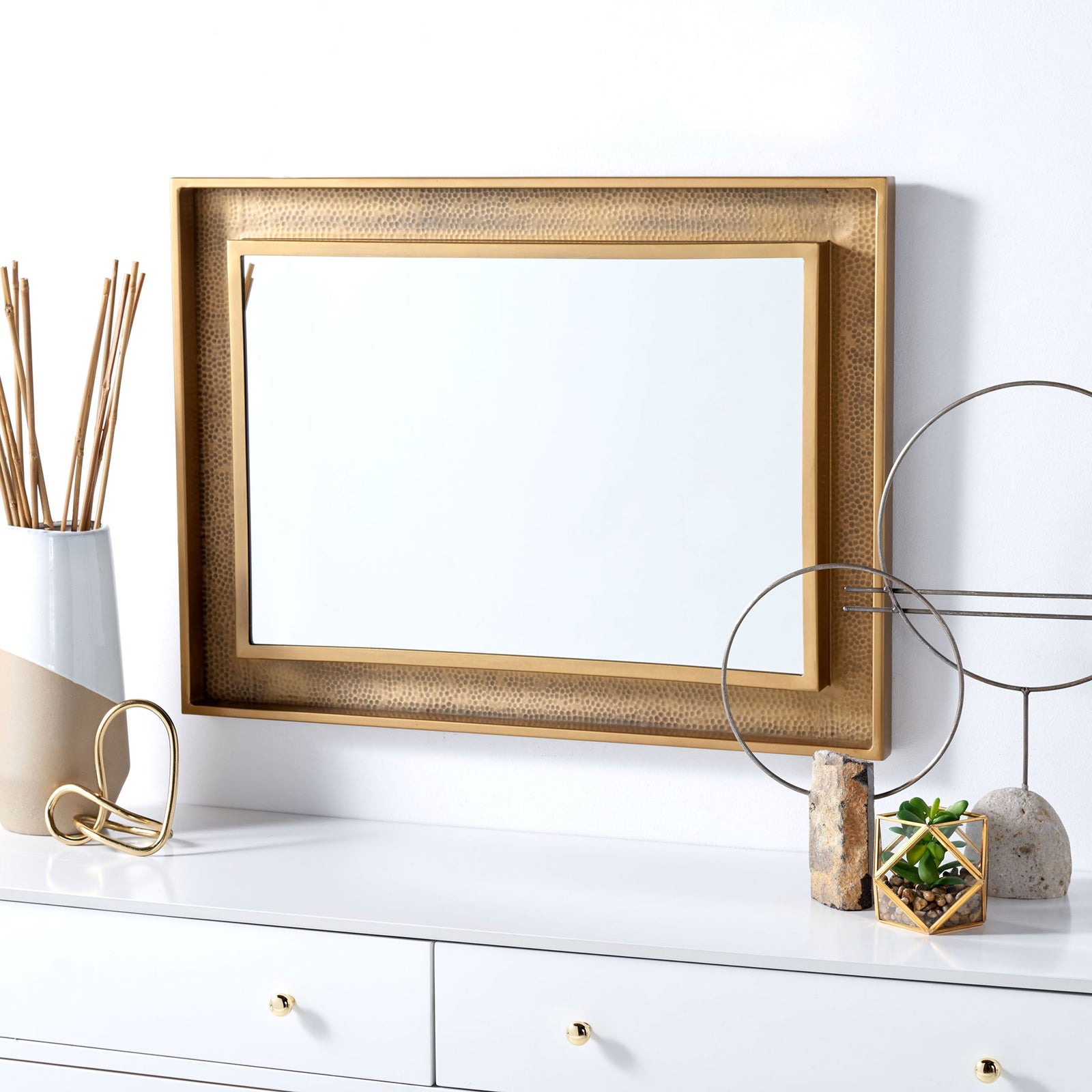Wall mirror hangs horizontally above a white cabinet, adding warmth with its textured brass finish. || MRR3049A || front_room
