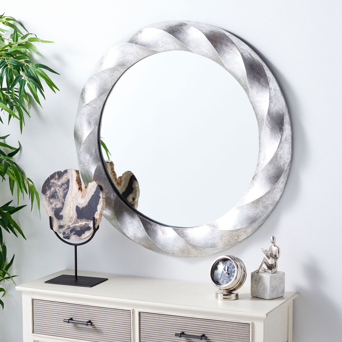 A sculpted silver mirror adds reflective light and texture above a console. || MRR3059A || front_angle_room