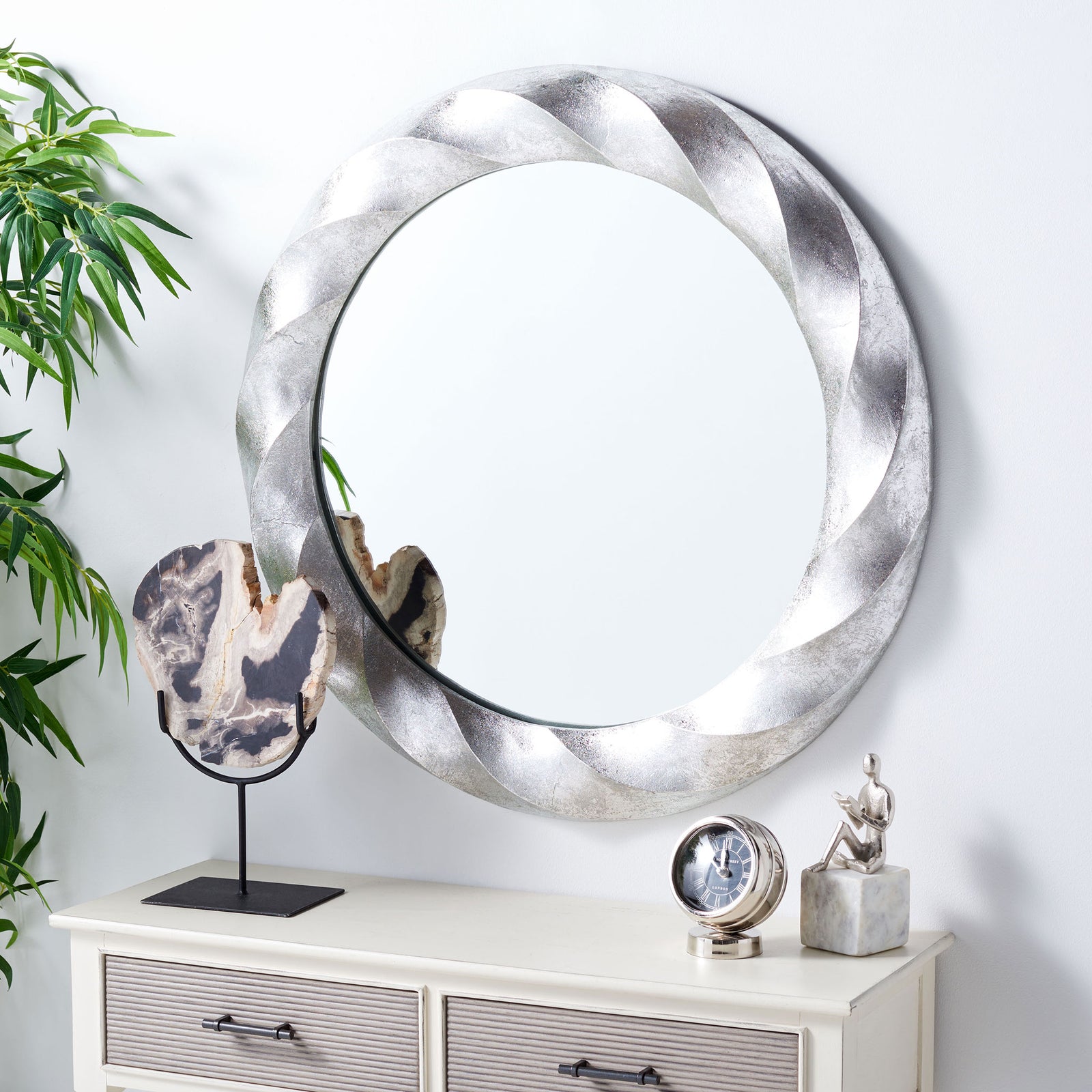 A sculpted silver mirror adds reflective light and texture above a console. || MRR3059A || front_angle_room