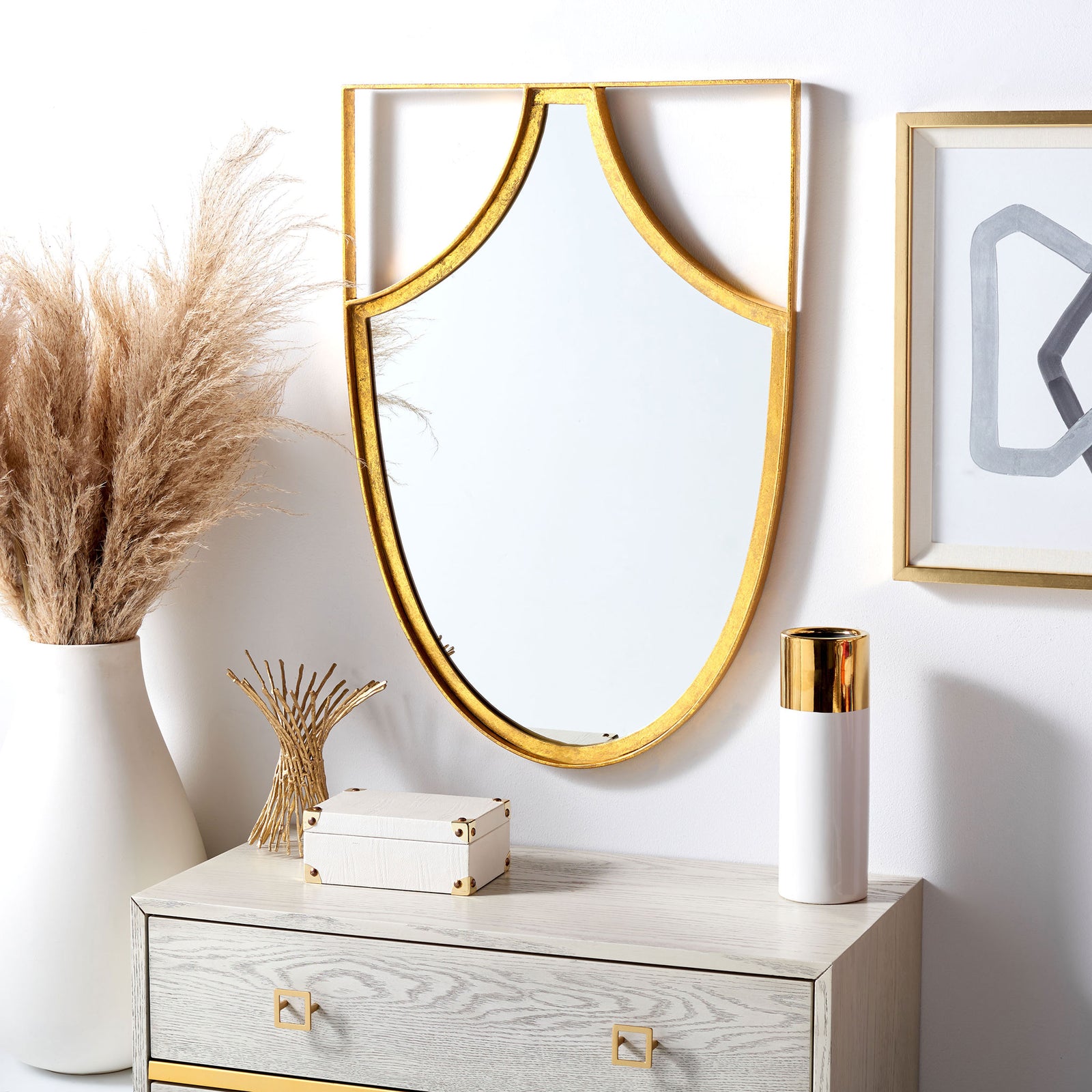 A gold-framed mirror brings graceful curves and a warm metallic accent above a light wood dresser || MRR3060A || front_room