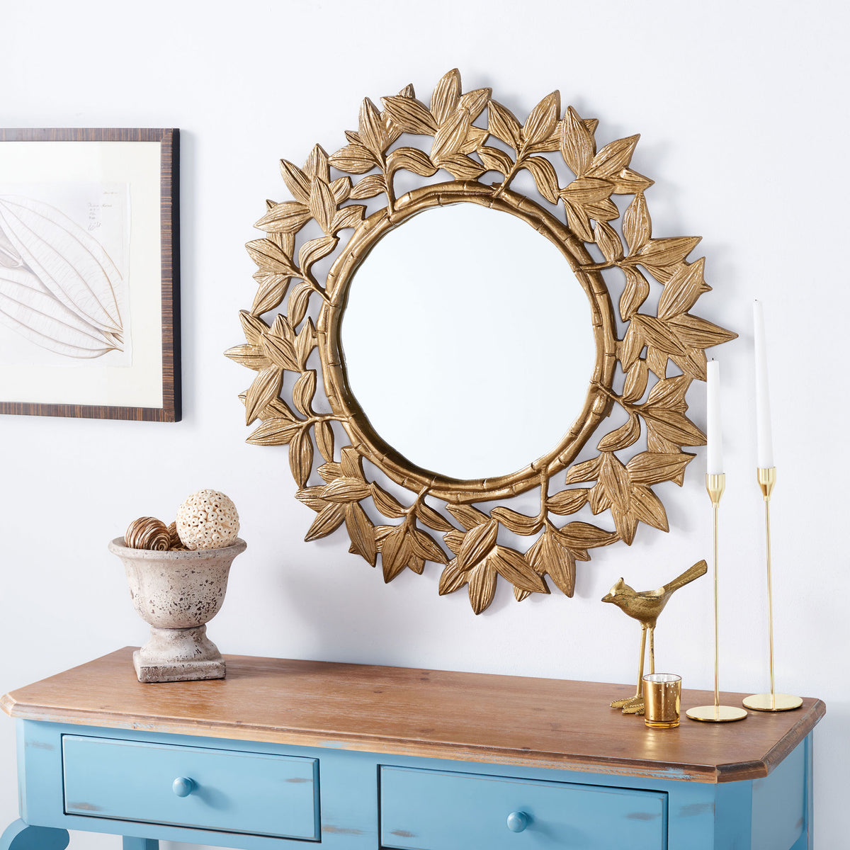 A round mirror with brass-toned foliage adds sculptural warmth above a blue console || MRR3062A || front_room