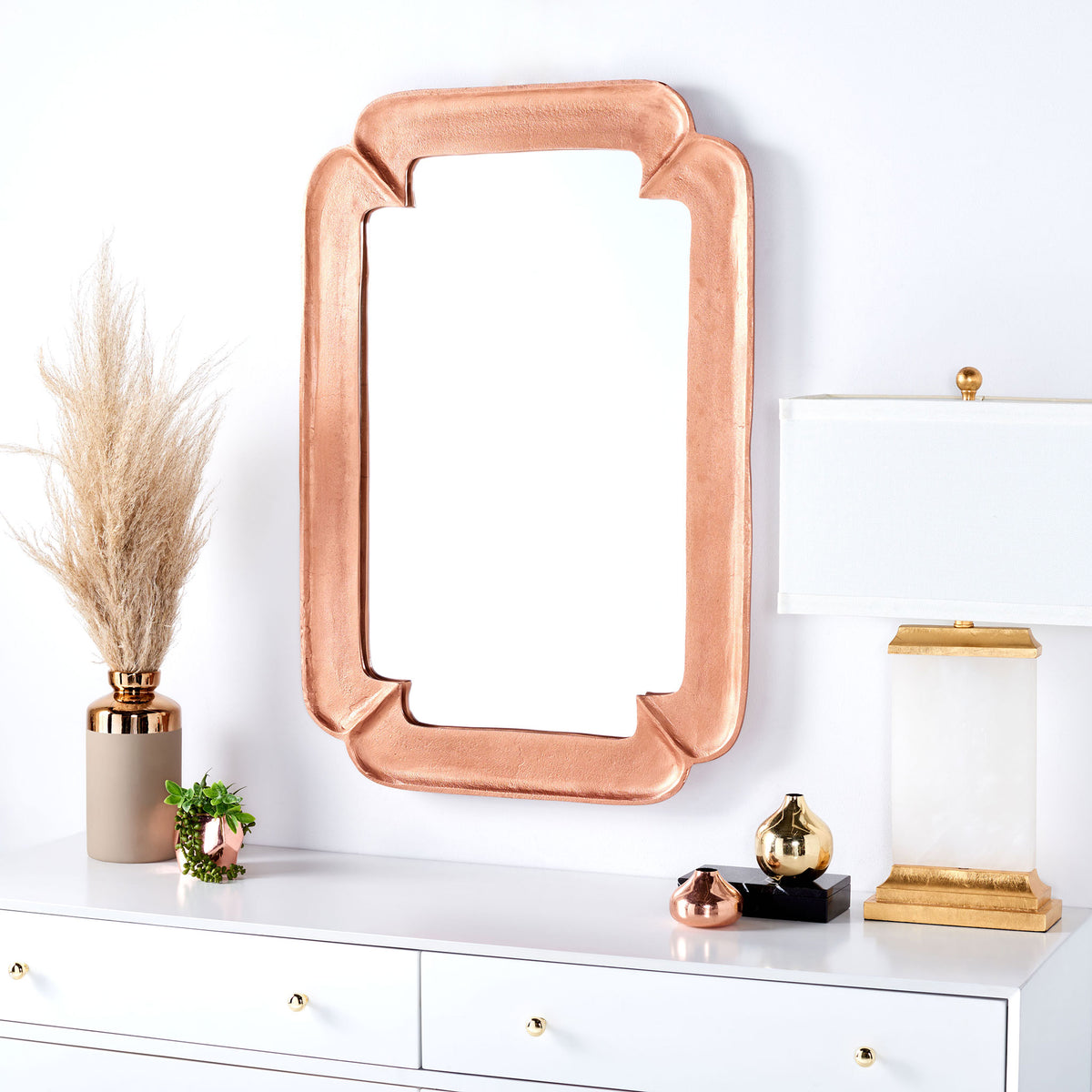 A sculptural copper-finish mirror adds warmth above a white dresser. || MRR3066A || front_room