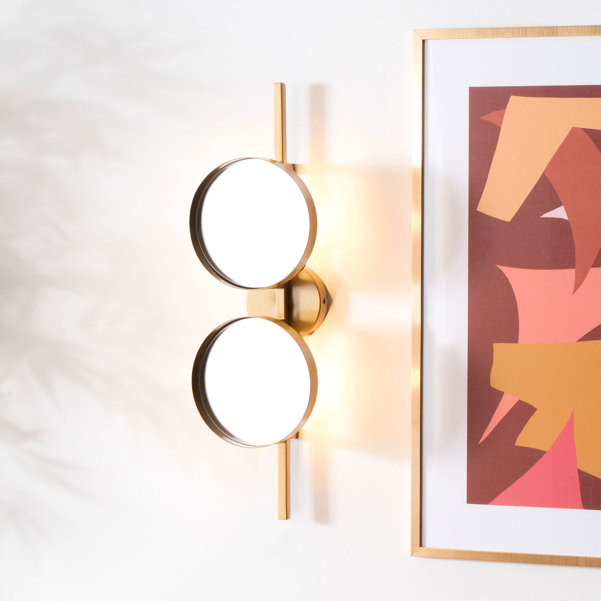 Warm light glows behind stacked round mirrors, adding a soft halo to the gold wall accent.