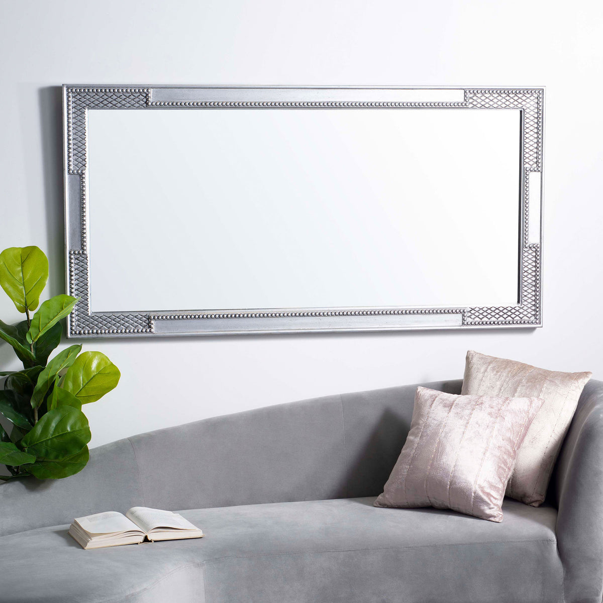 Silver wall mirror mounted horizontally, with a slender frame and intricate geometric accents