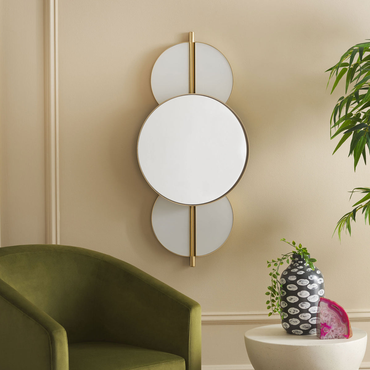 A gold-rimmed round mirror and white circular accents add airy geometric style to a living room wall