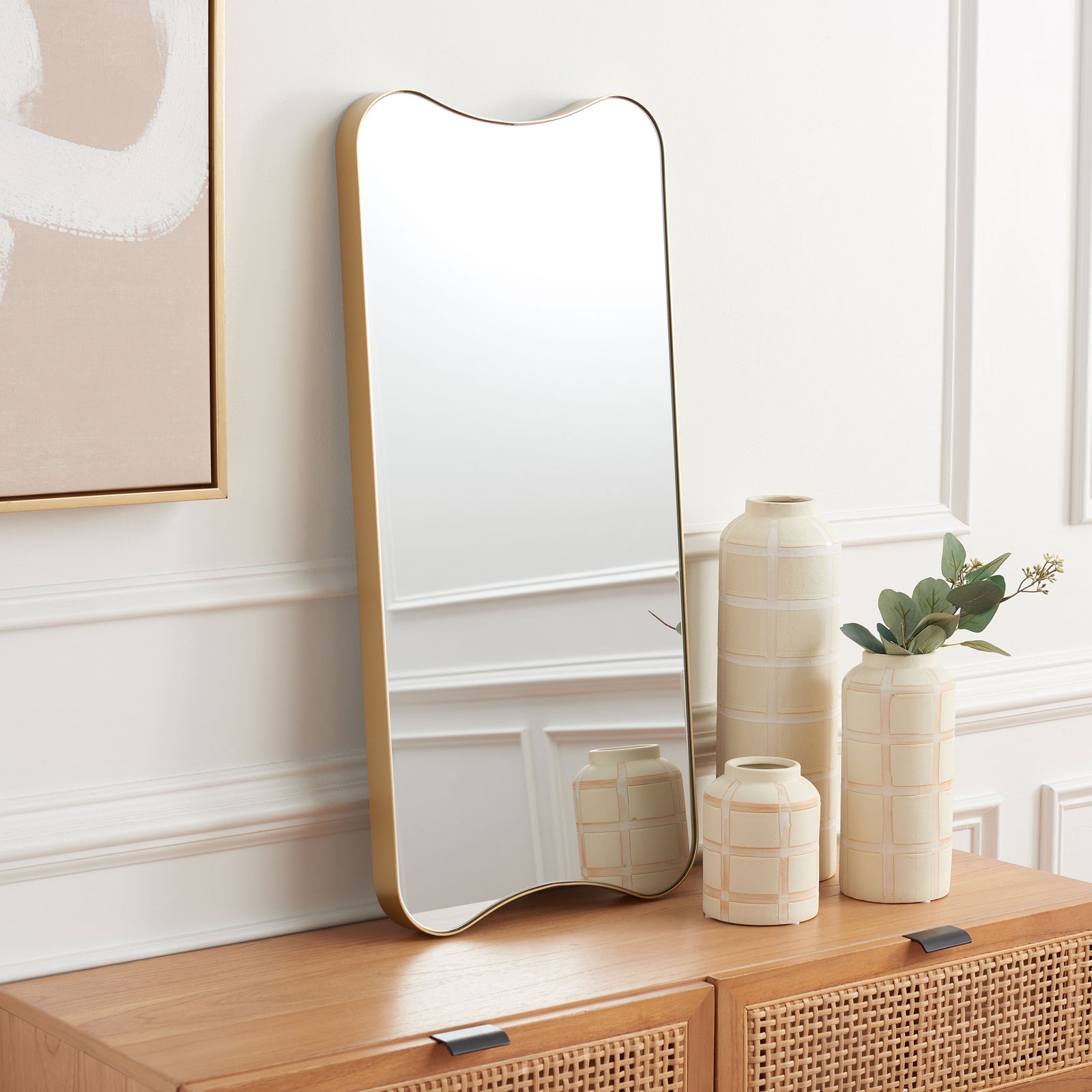 A tall mirror with a sculptural gold frame adds a warm accent to a wooden console || MRR8008A || front_angle_room