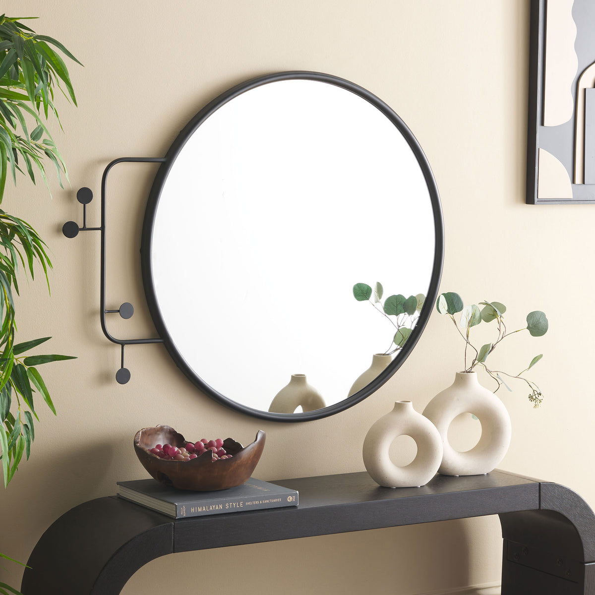 A circular black mirror with asymmetrical, disc-tipped iron accents brings graphic style to the wall.