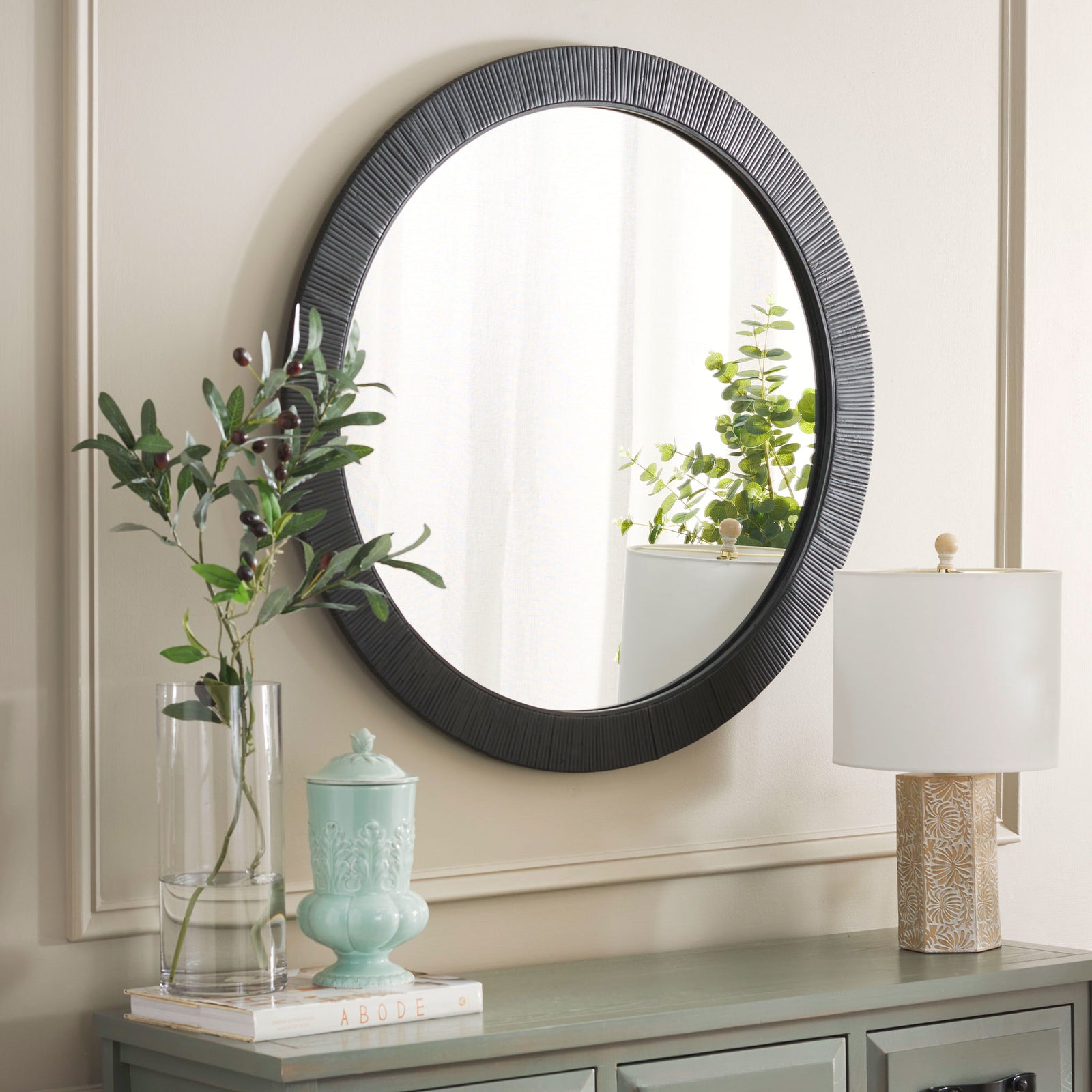 A textured black frame lends contrast to this round mirror above a console table. || MRR9002A || front_angle_room