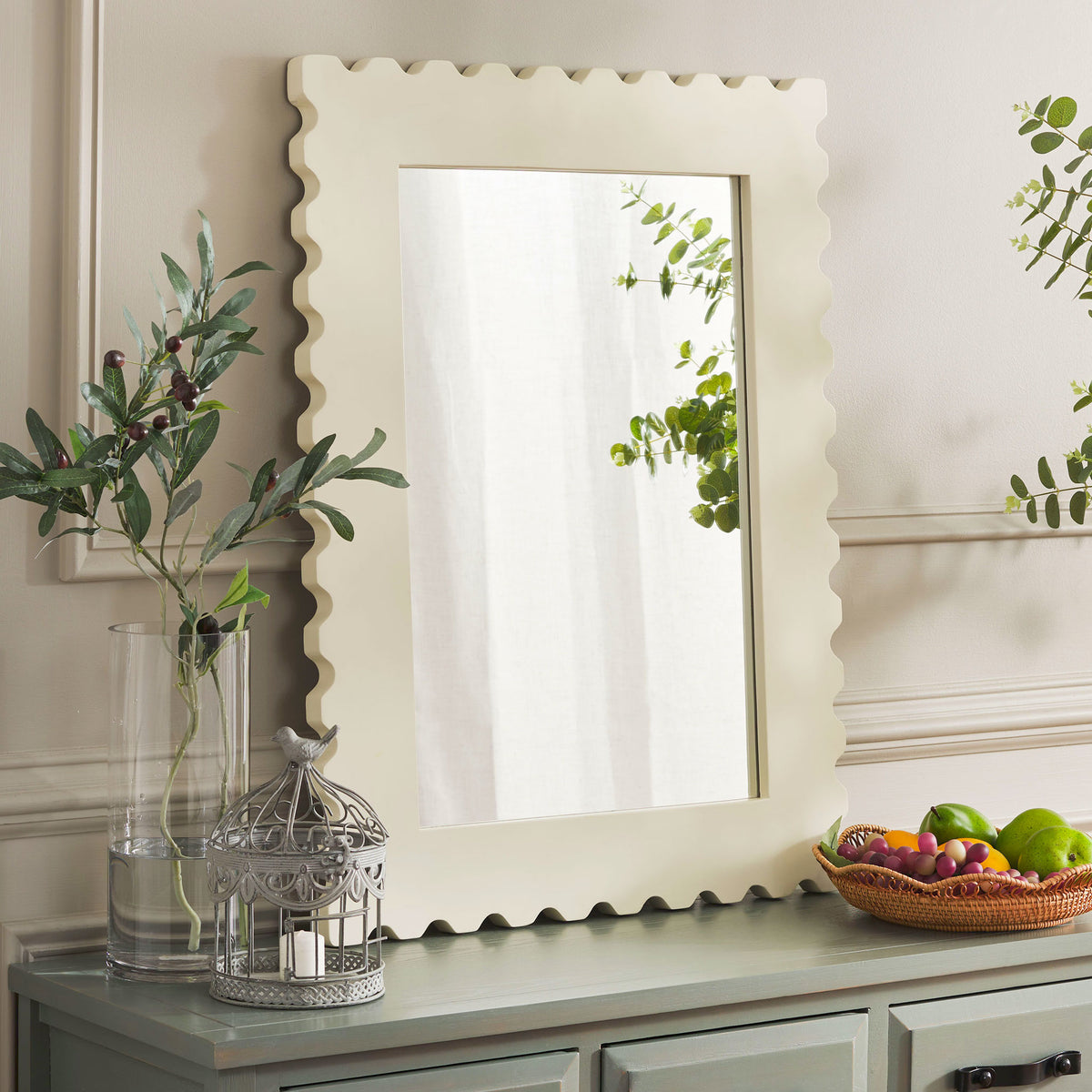 Cream scalloped mirror adds a softly sculpted accent alongside greenery and a painted console || MRR9005B || front_room