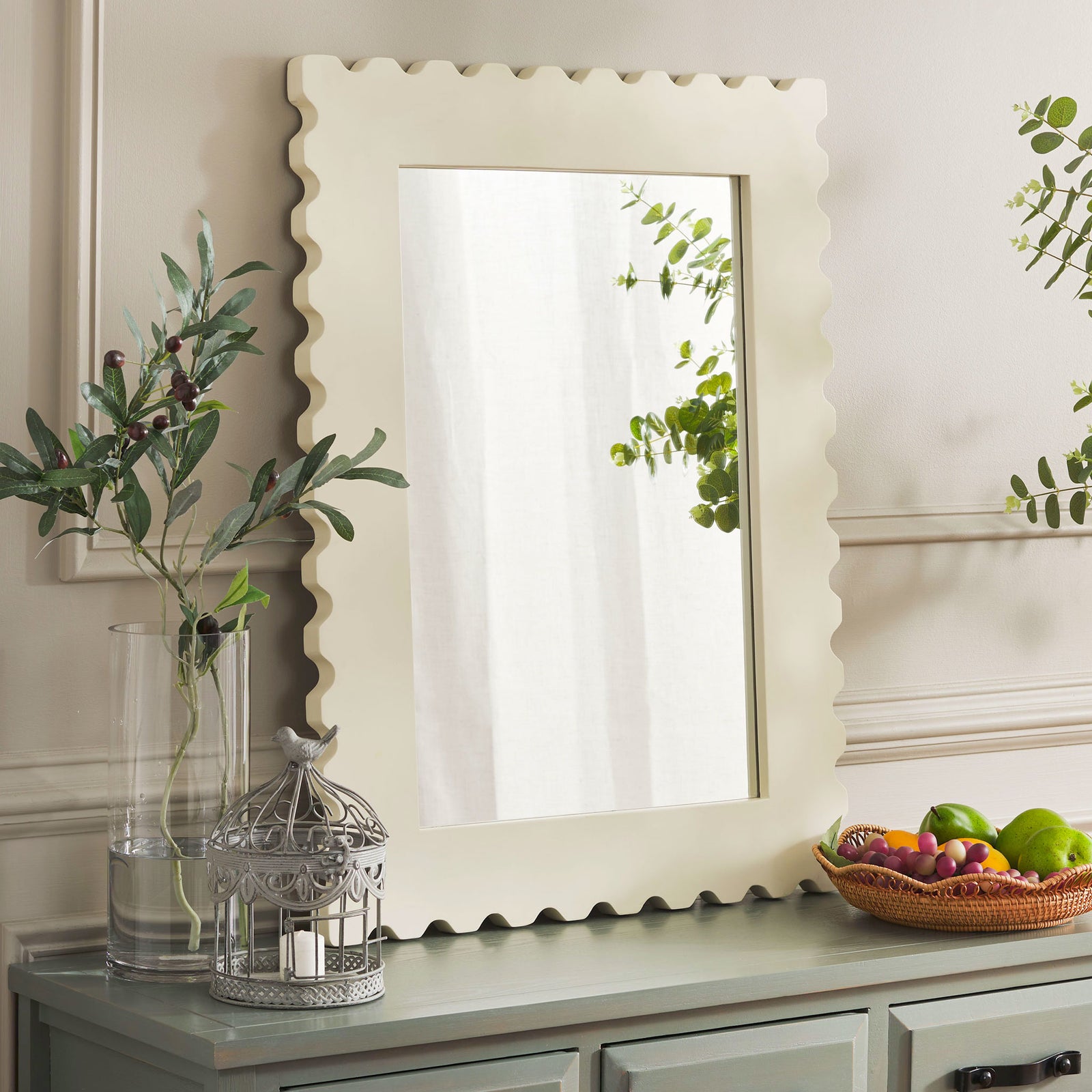 Cream scalloped mirror adds a softly sculpted accent alongside greenery and a painted console || MRR9005B || front_room