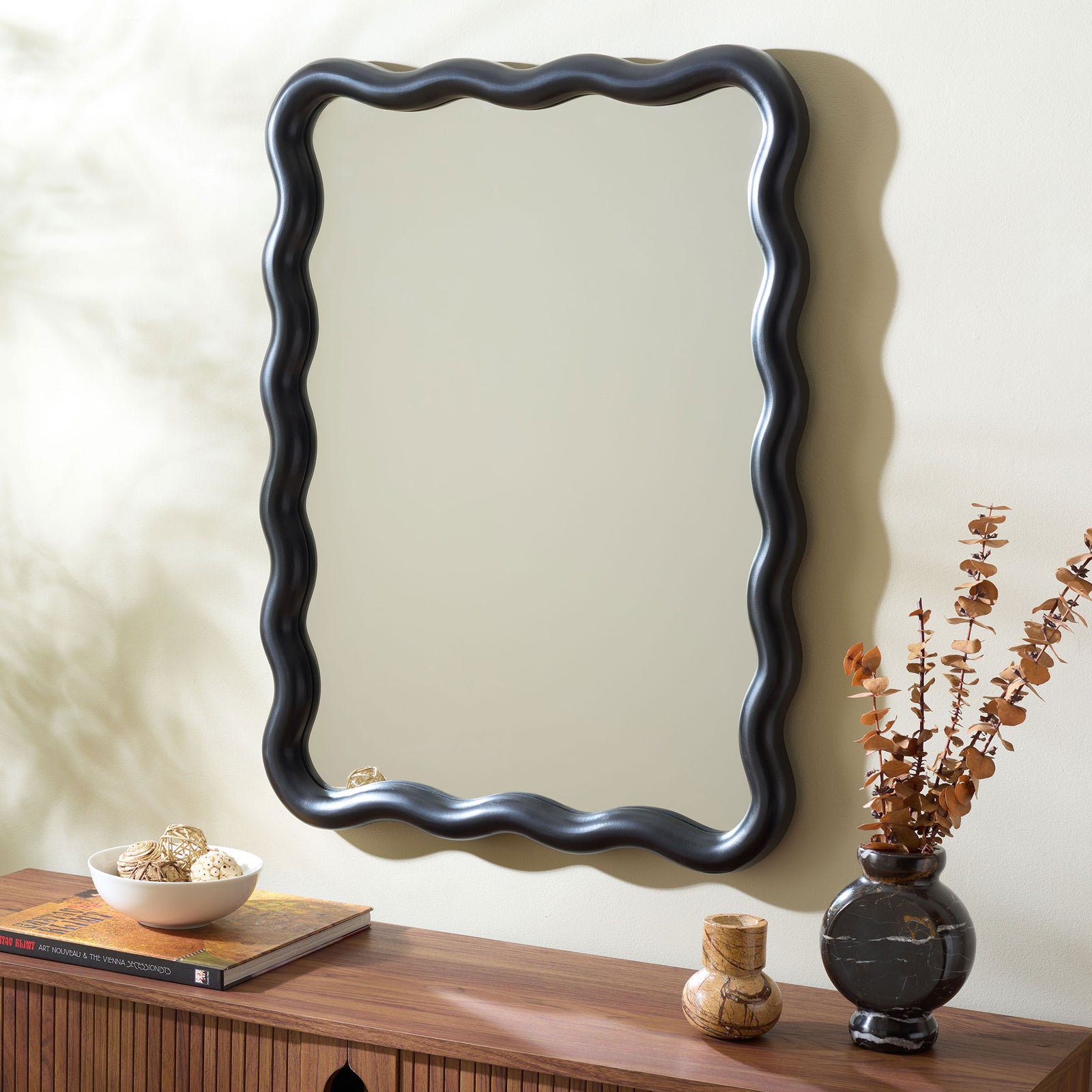 Wavy black wall mirror adds striking contrast above a wood console || MRR9007B || front_angle_room