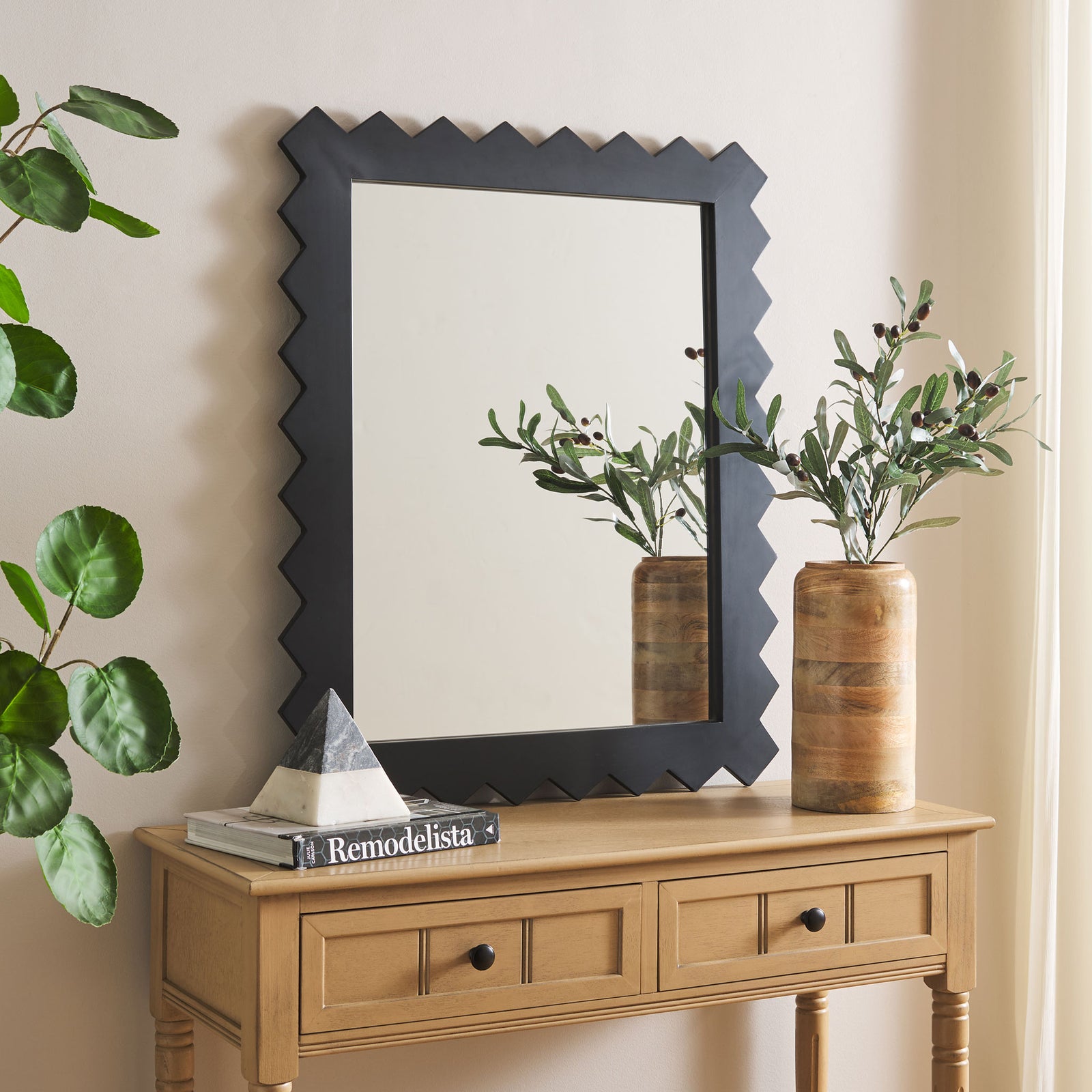 Black zigzag-framed mirror adds a graphic accent above a light wood console. || MRR9010A || front_room