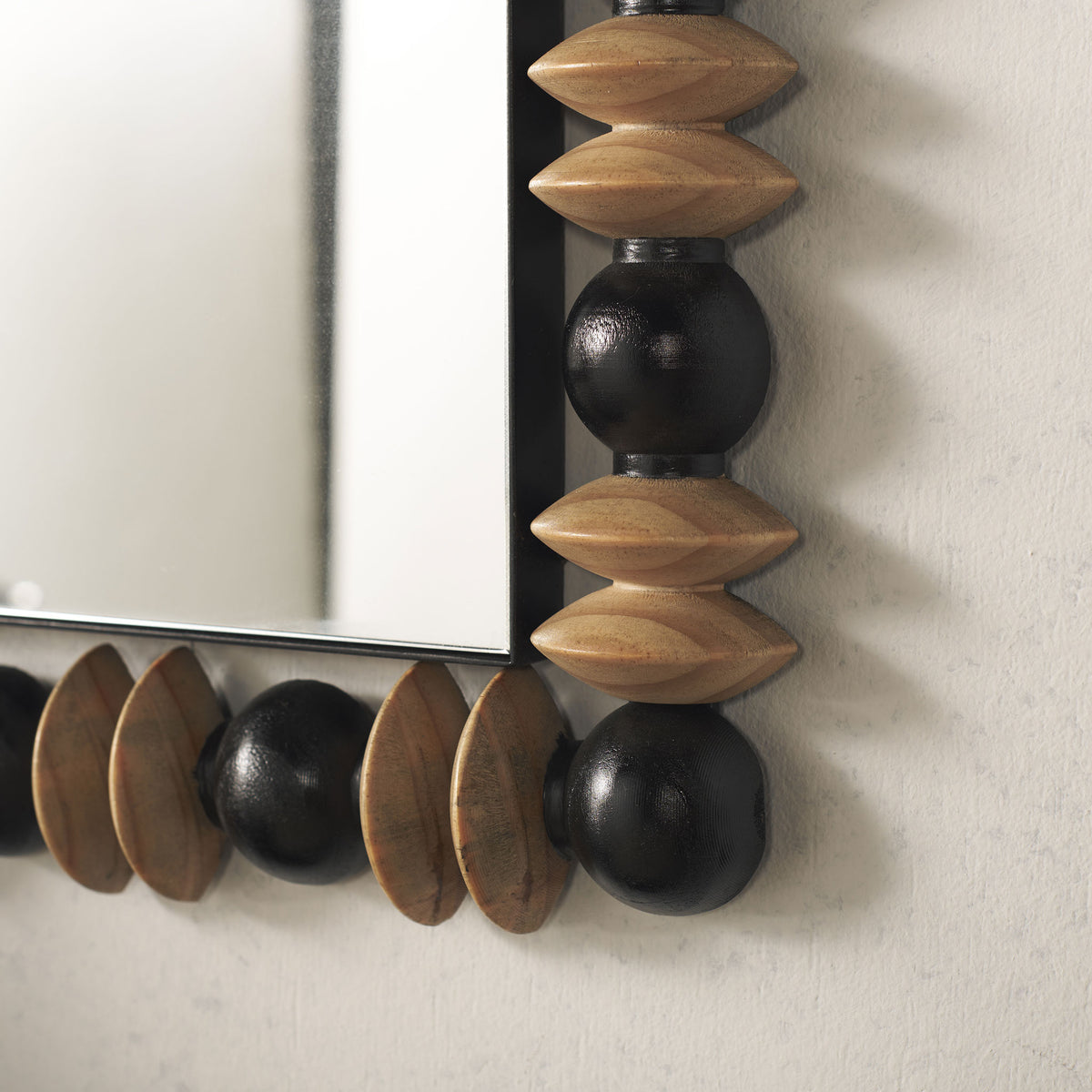 Paired natural wood discs and rounded black beads lend earthy texture to the mirror's lower edge.