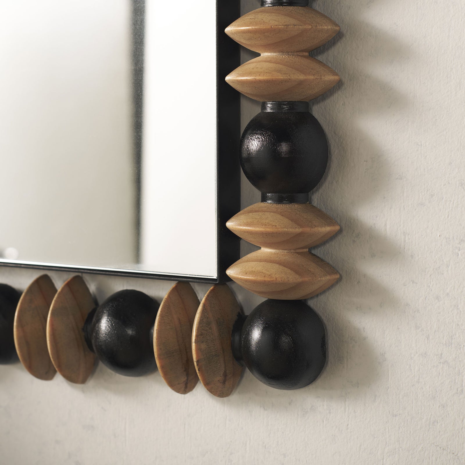 Paired natural wood discs and rounded black beads lend earthy texture to the mirror's lower edge. || MRR9011A || detail_room