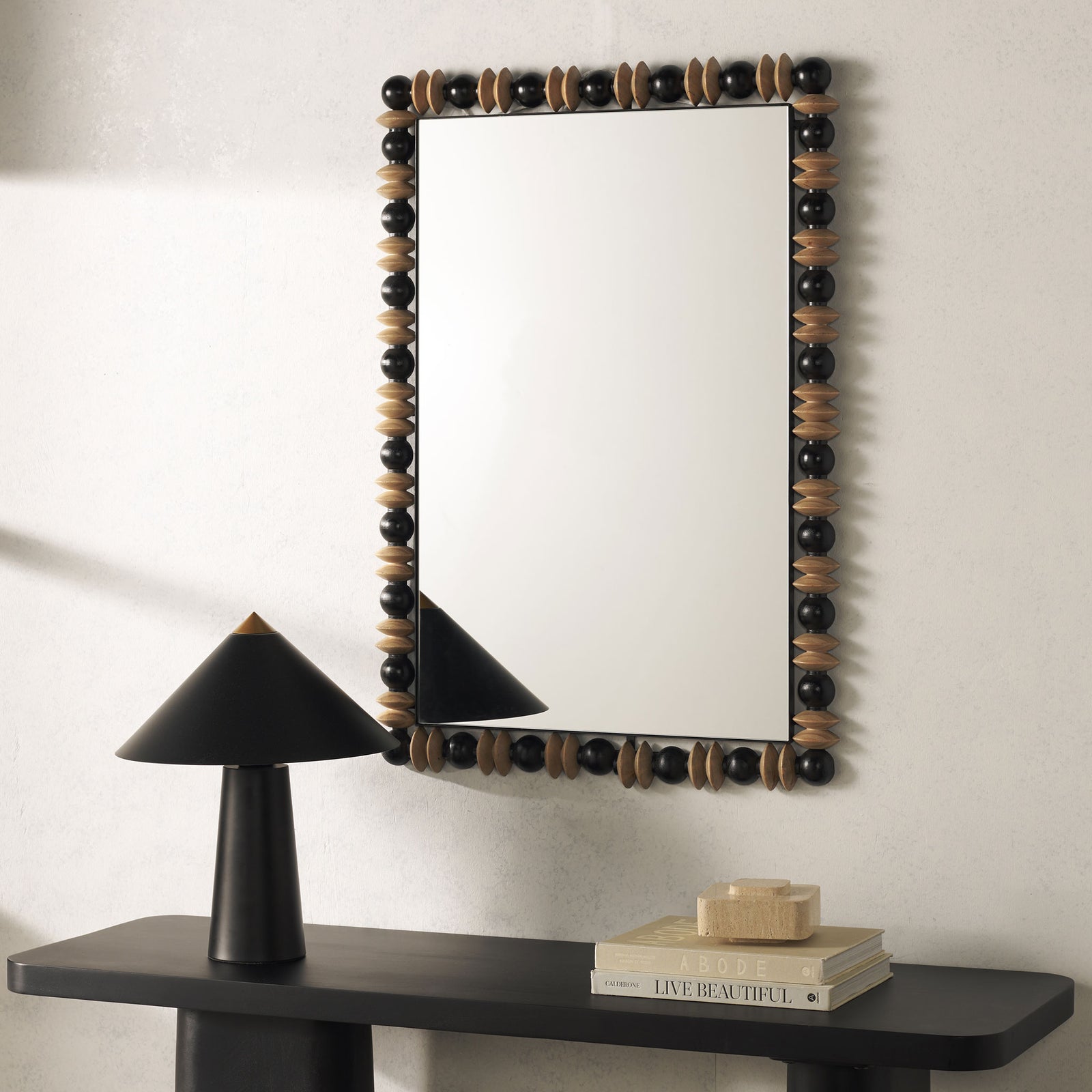 A black and natural wood mirror brings an organic accent to the wall above a slim console. || MRR9011A || front_room