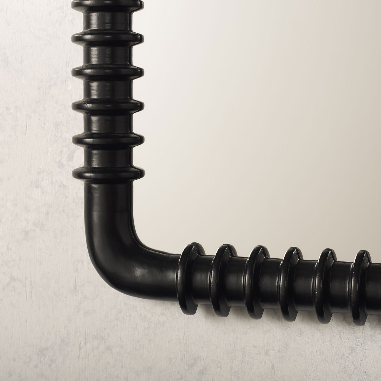 A rounded corner and raised rings give the black mirror frame sculptural texture. || MRR9024A || detail_room