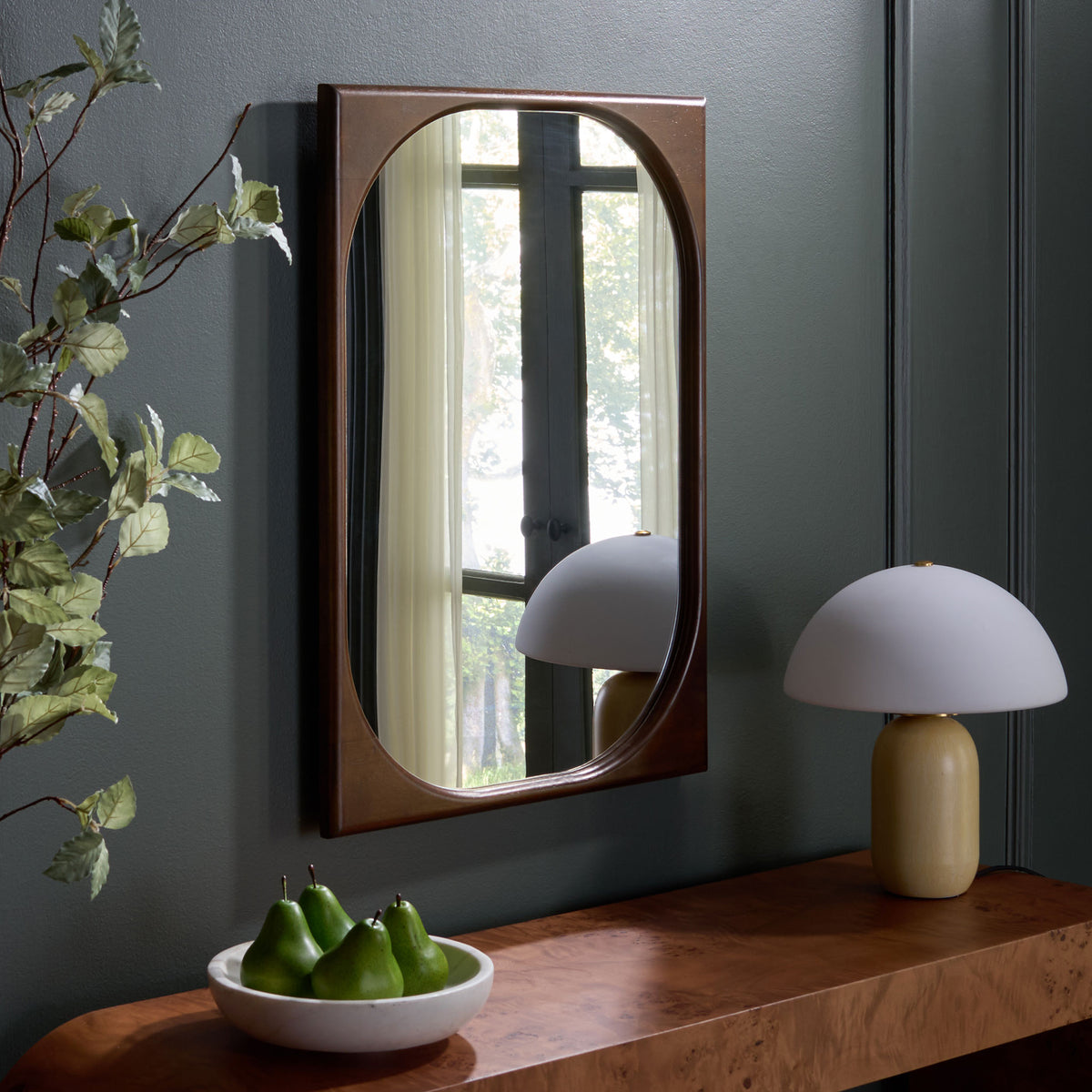 A brown-framed mirror brings warmth and reflected light above a wood console.