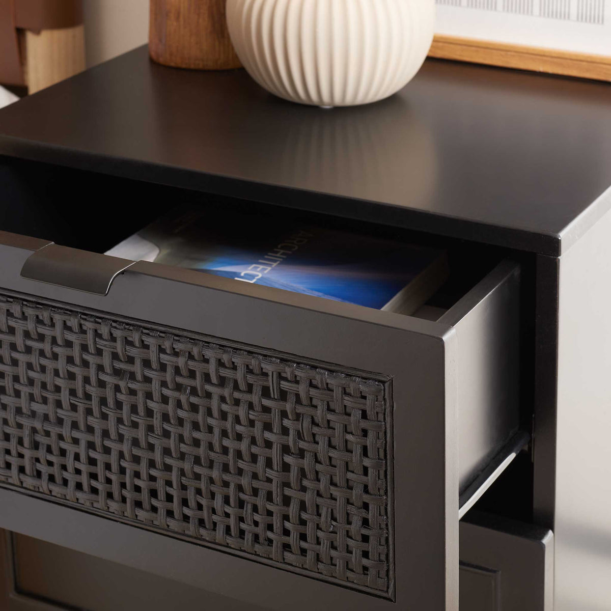 Textured rattan drawer adds coastal character to this sleek black nightstand.