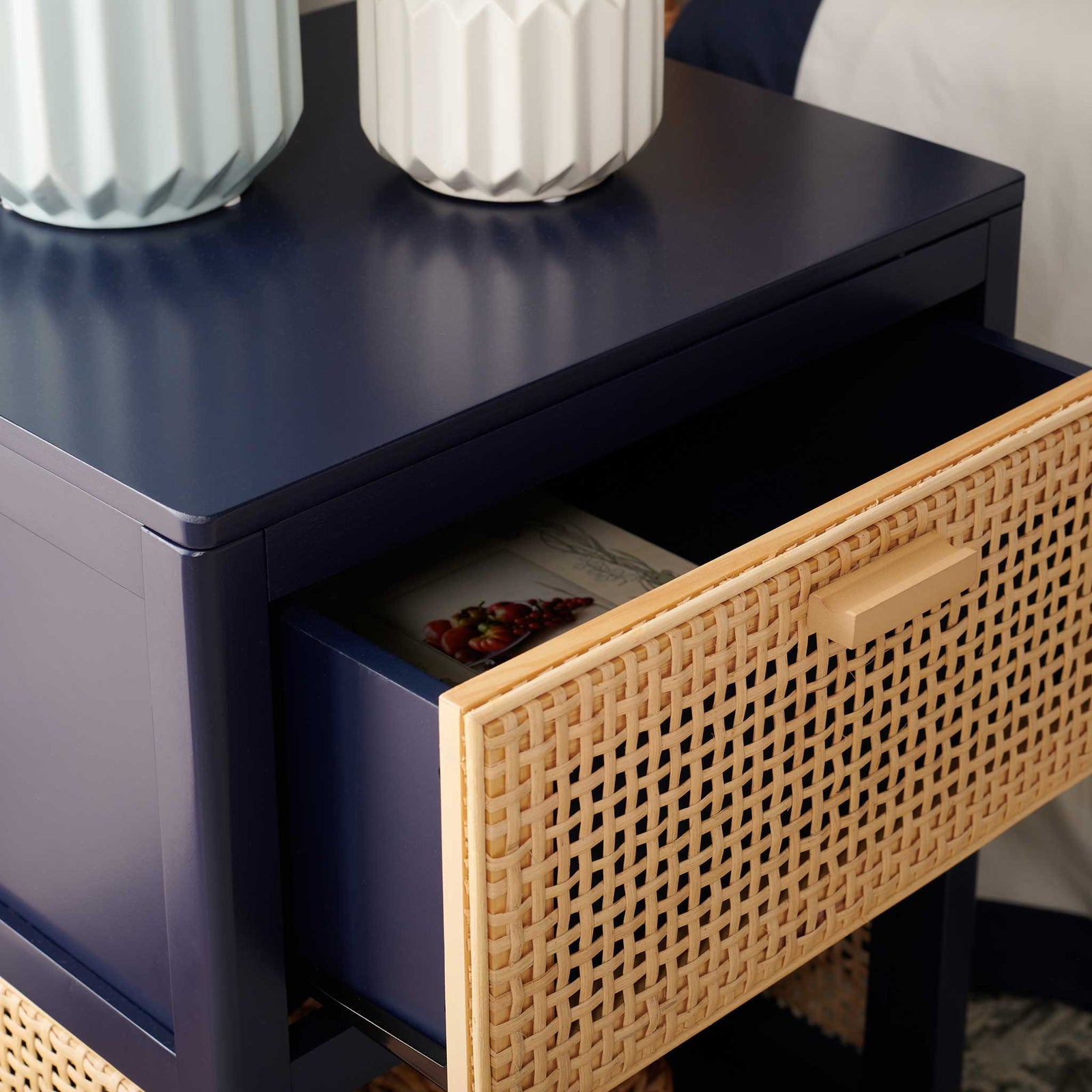 Open drawer reveals smooth interior beneath a sleek navy top and textural rattan front || NST5012E || storage_open_room