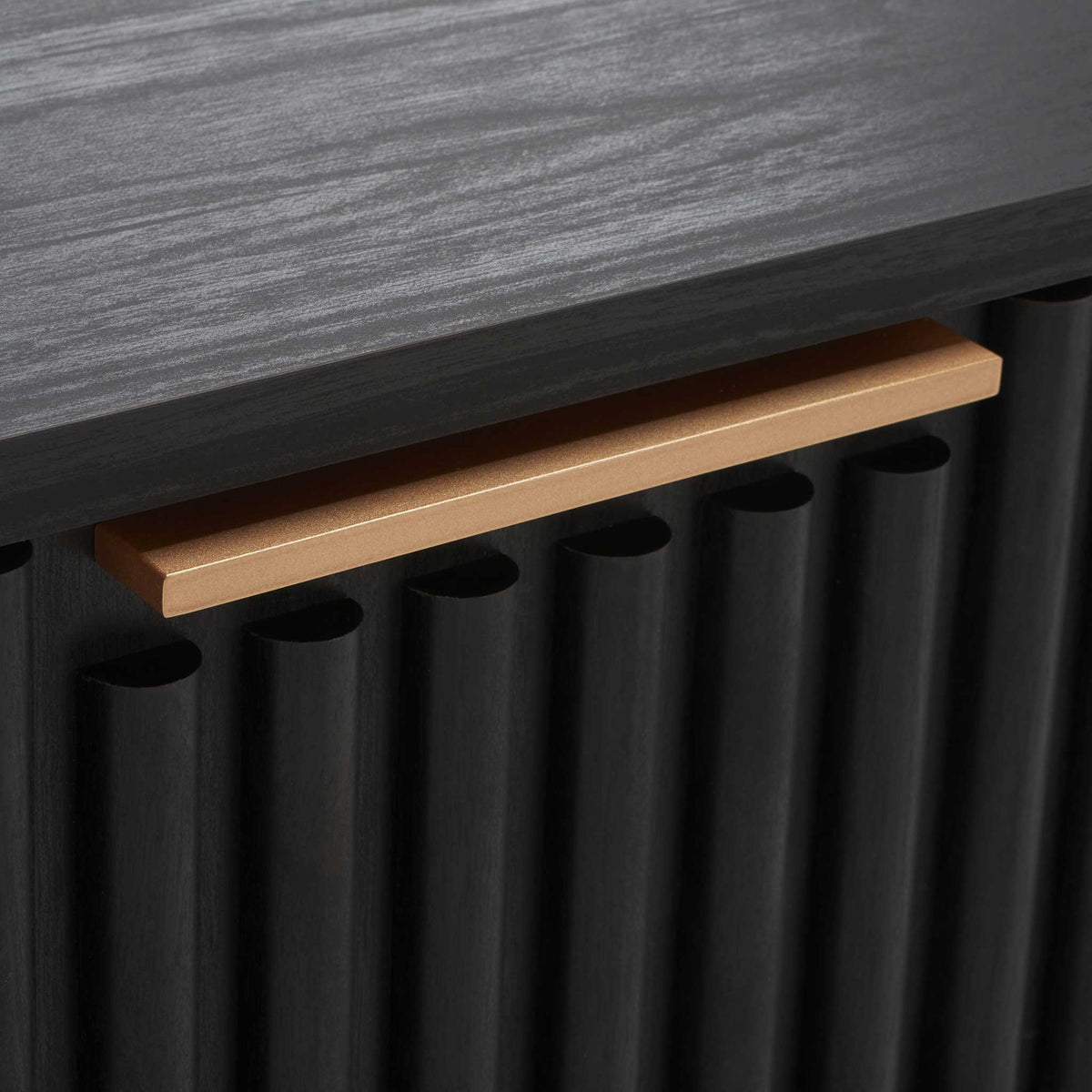 Long matte gold bar pull adds a refined contrast to the black fluted drawer face || NST9605B || handle_studio