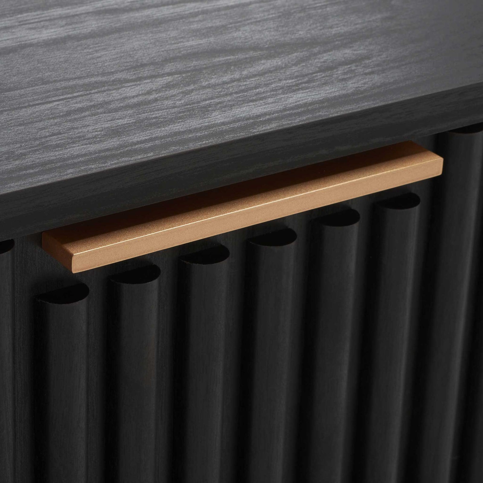 Long matte gold bar pull adds a refined contrast to the black fluted drawer face || NST9605B || handle_studio