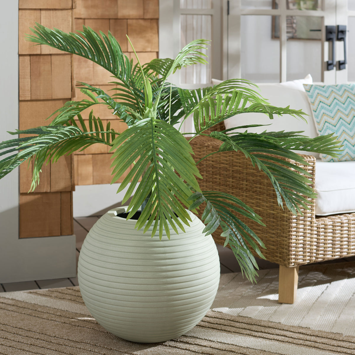 Pale sage planter pairs gentle ribbing with wide palm fronds for a calming greenery display. || PAT1534E || front_room