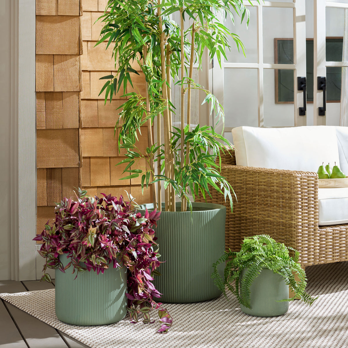 Green fluted planters hold vibrant foliage by a woven patio lounge chair. || PAT4600C-SET3 || front_room