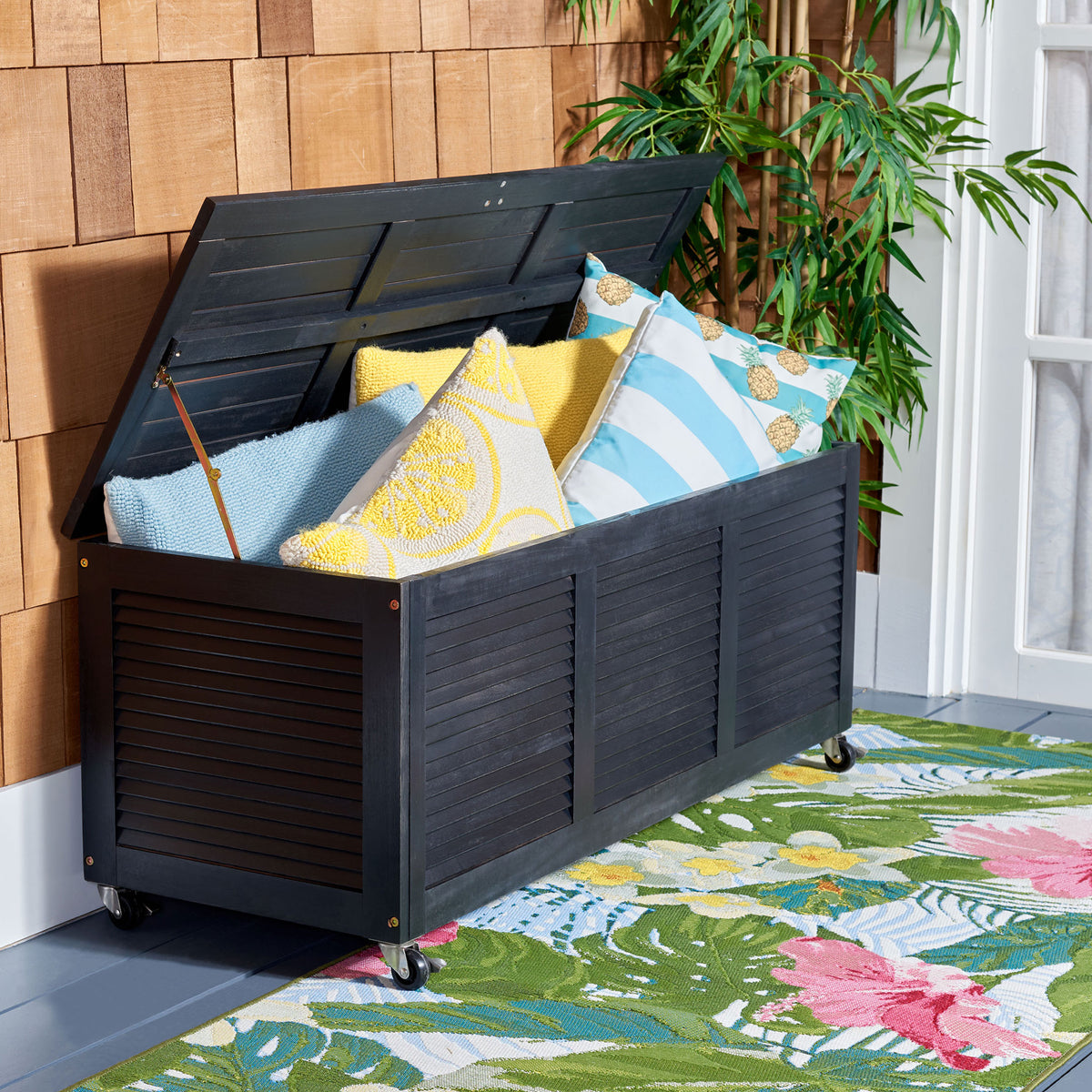 Lift-up lid reveals roomy cushion storage inside the black wheeled wood chest
