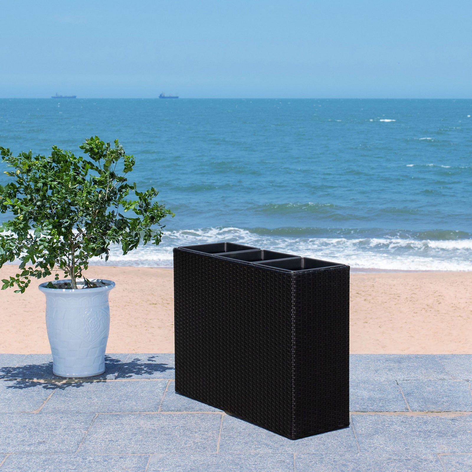 Slim black wicker planter adds modern structure to an open-air coastal space. || PAT7705A || front_angle_room