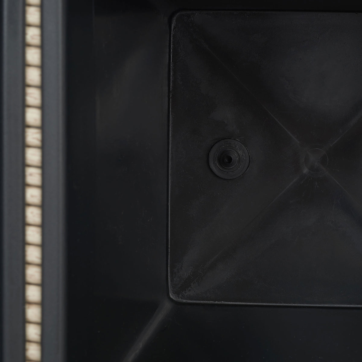 A molded black planting insert features a recessed circular drain opening. || PAT7705B || detail_studio