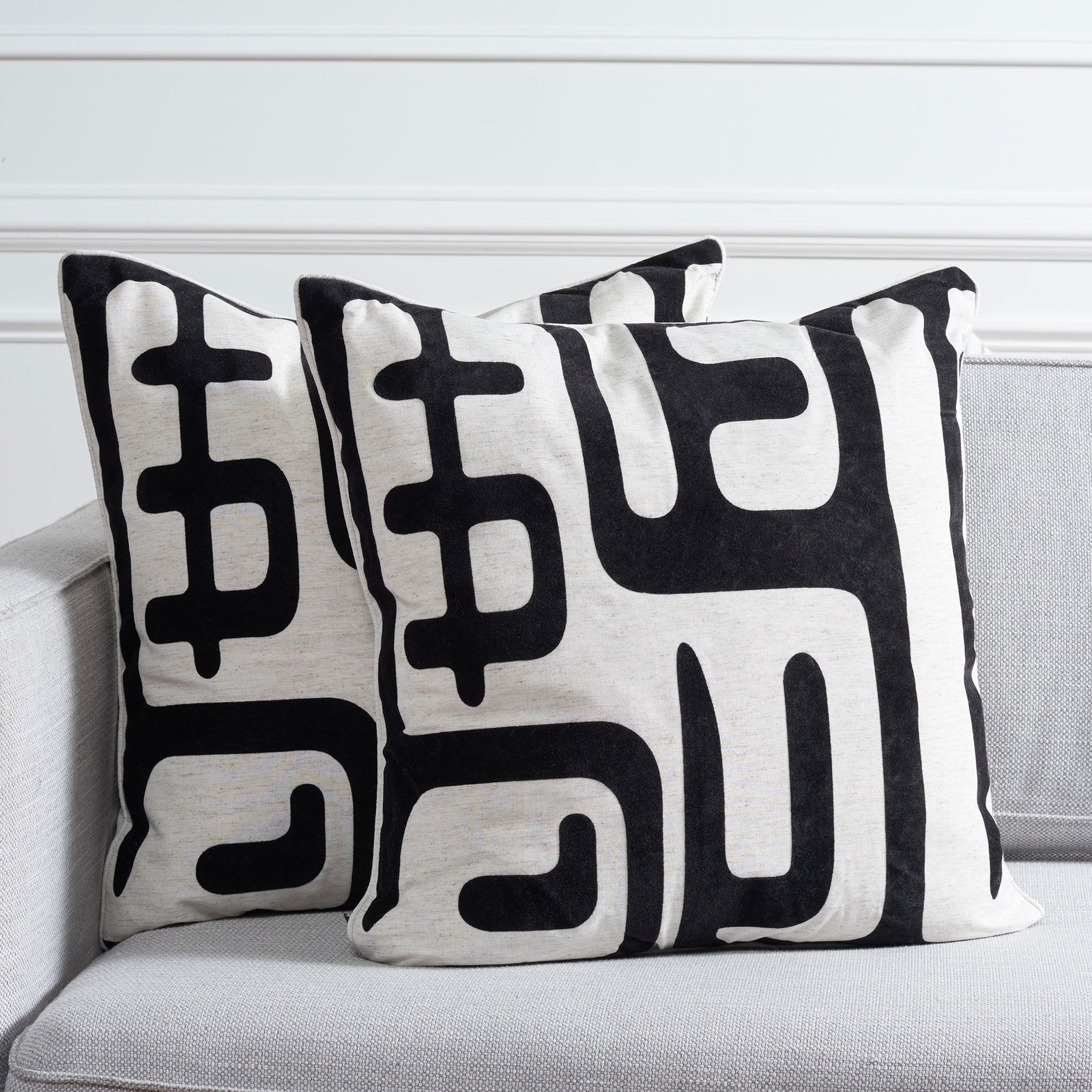 A pair of ivory pillows with bold black abstract motifs adds graphic contrast to a sofa || PIL162A-2222-SET2 || front_multi_room