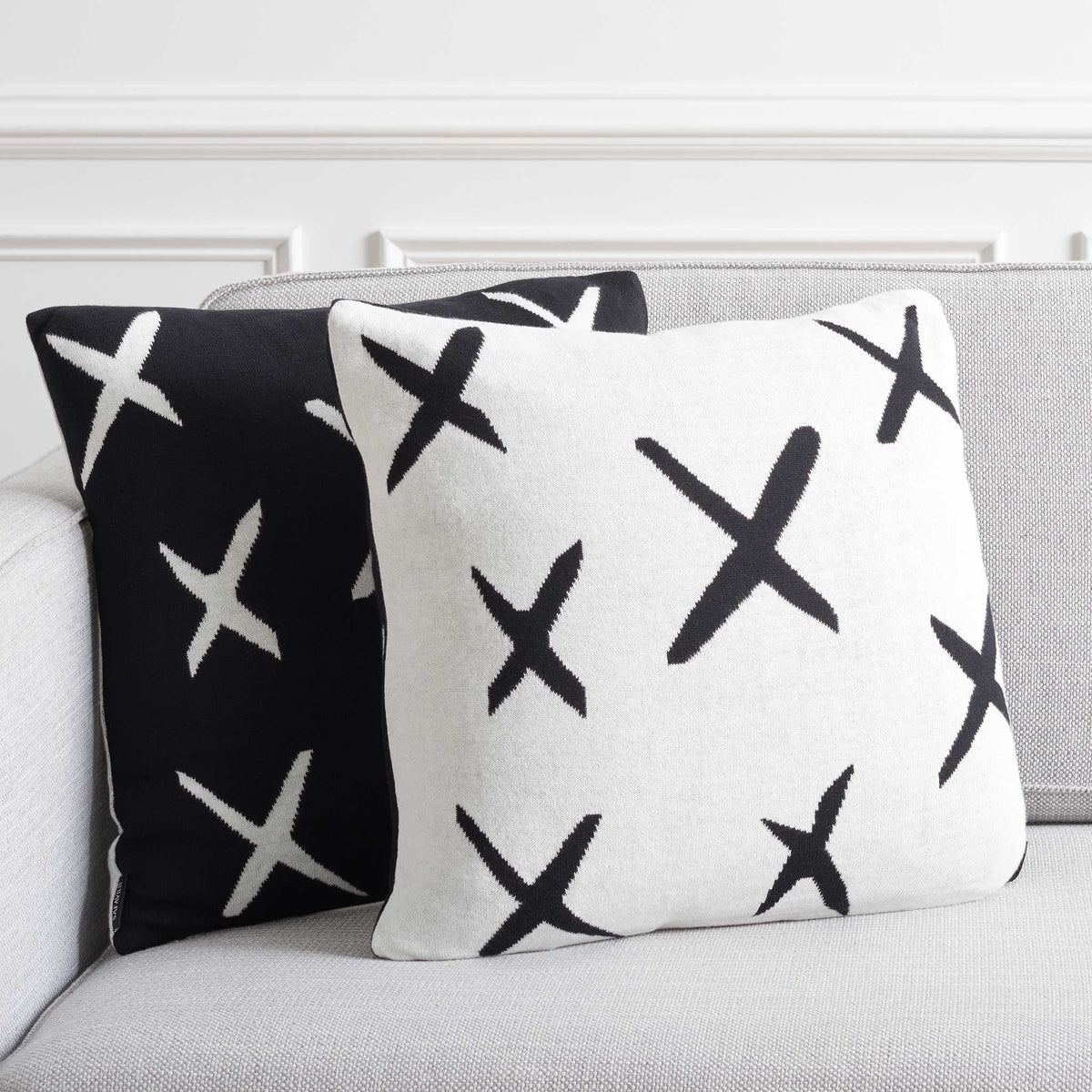 Black and ivory X-pattern pillows styled together for a striking two-tone look. || PLS404A-1818-SET2 || back_angle_multi_room