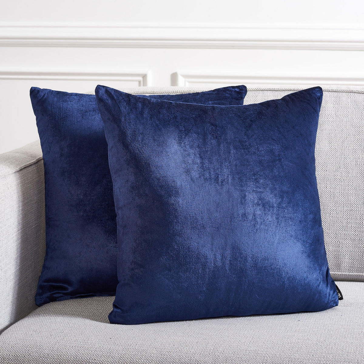 Two navy accent pillows add rich color and soft texture to a neutral sofa.