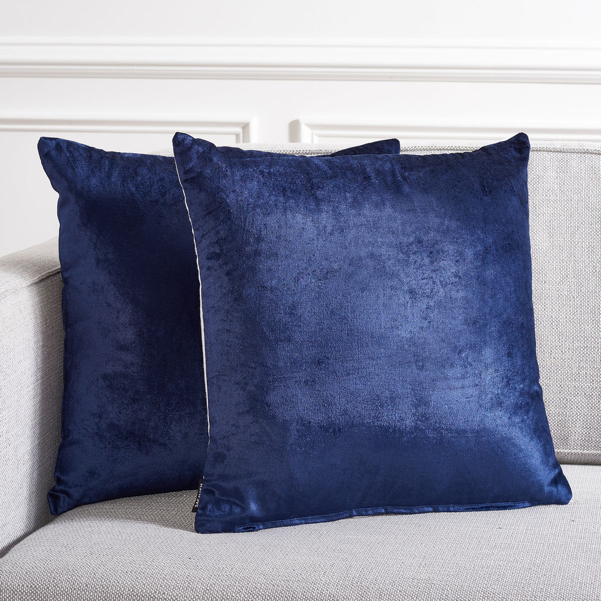 Two navy pillows bring a bold, lustrous accent to pale upholstered seating
