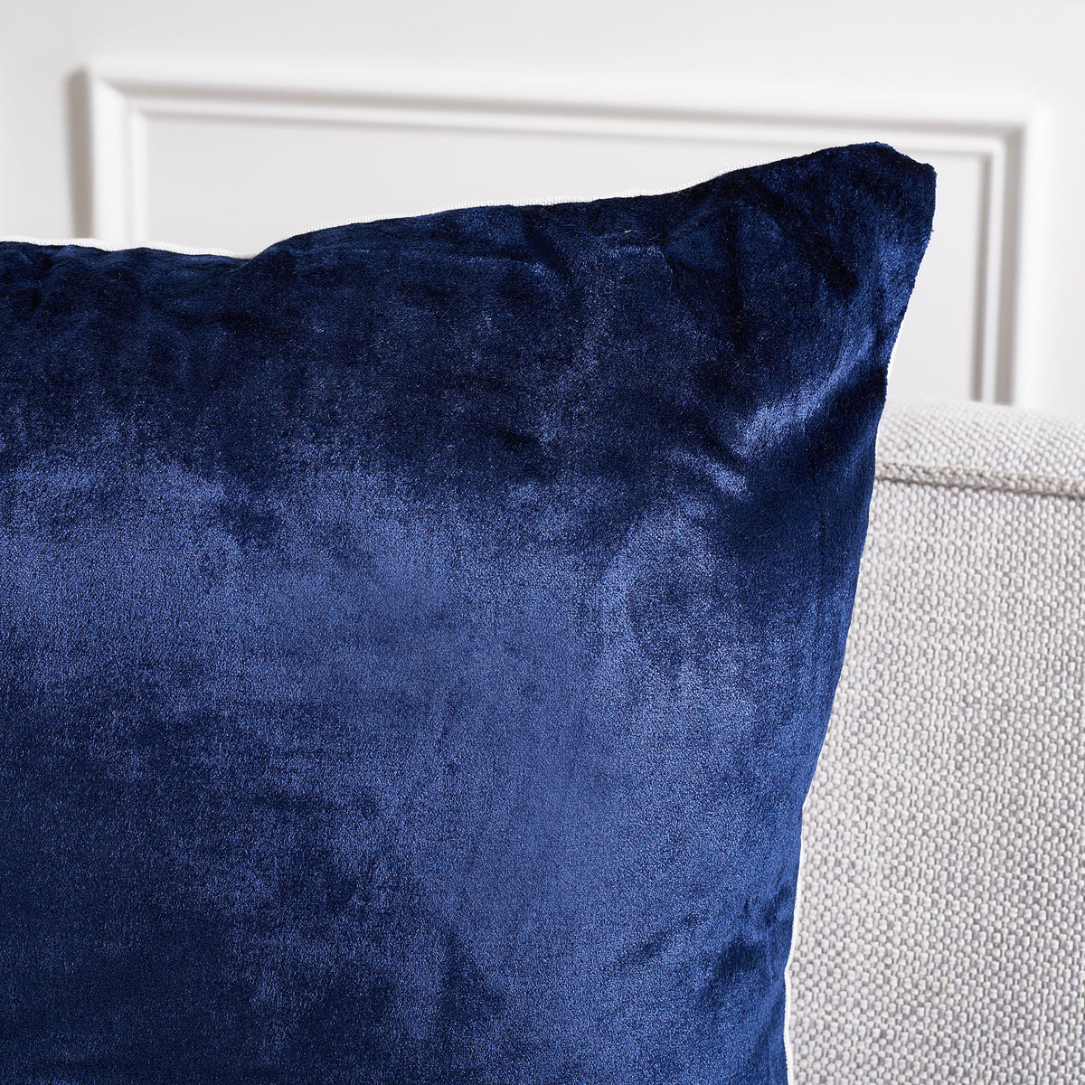 Rich navy fabric shifts in the light across the pillow's softly shaped corner