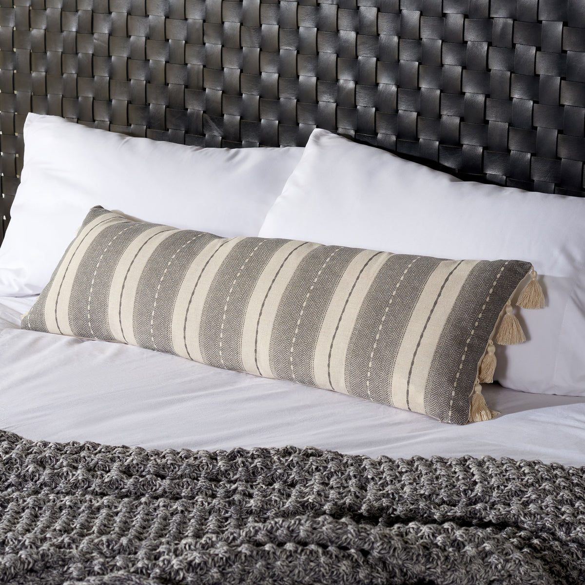 Woven gray and beige stripes and cream tassels bring cozy pattern to a bedroom