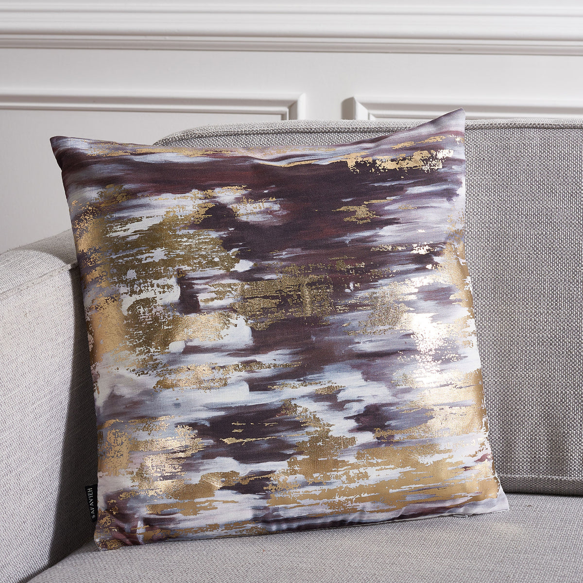 An abstract navy, gray and gold pillow brings a glamorous touch to a neutral sofa.
