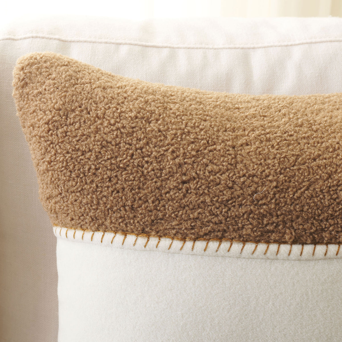 Plush camel fabric meets smooth ivory at a decorative stitched seam