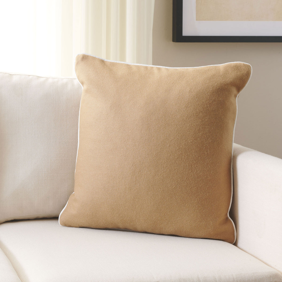 A camel wool accent pillow brings cozy texture and subtle contrast to a pale sofa.