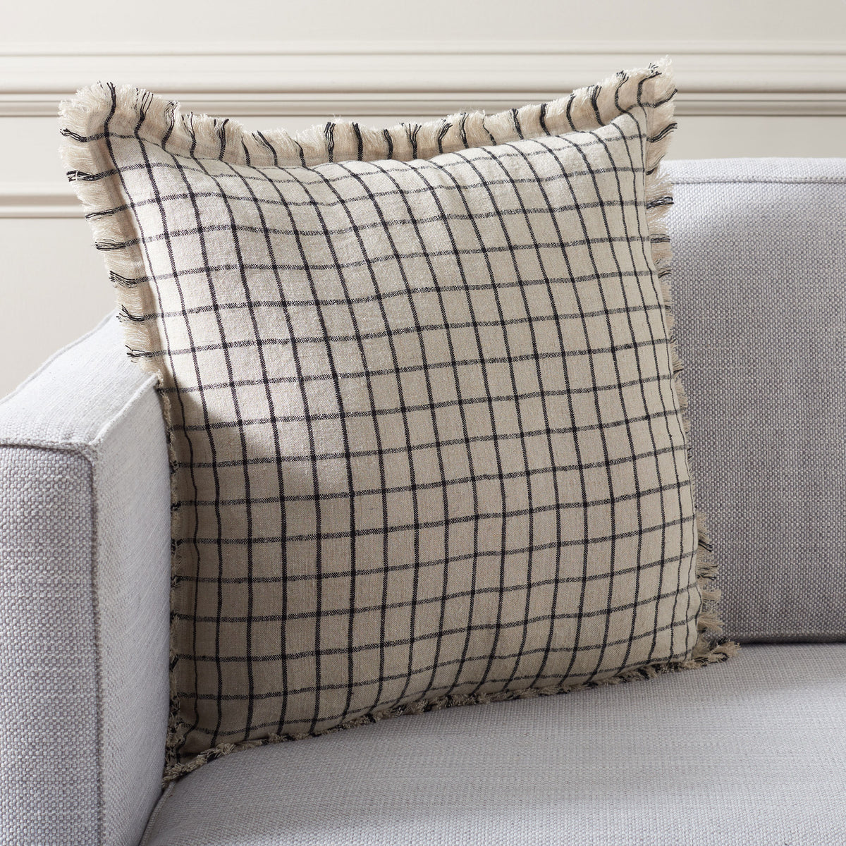 A natural linen pillow with black windowpane checks brings graphic softness to an upholstered sofa