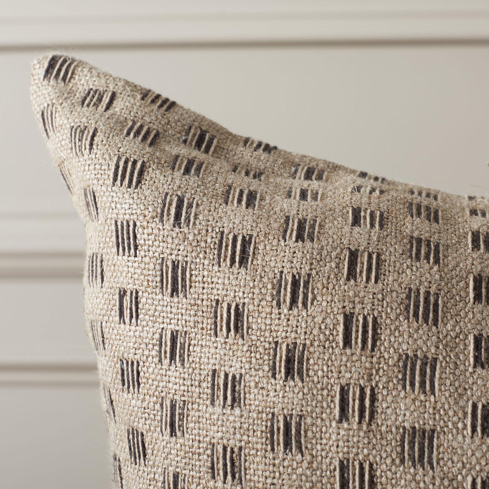 Natural linen weave and raised black dash motifs create tactile contrast across the pillow. || PLS8011A-2424 || detail_room