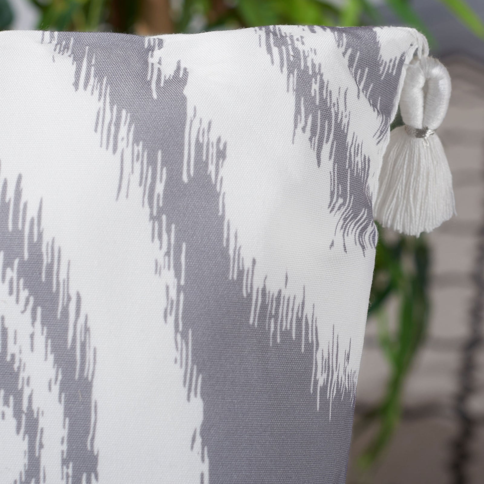 A white corner tassel accents the pillow's woven gray-and-white pattern || PPL261A-1818 || detail_room