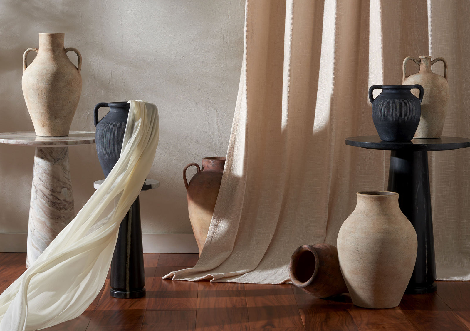 Charcoal vases with twin handles punctuate a warm mix of earthy ceramics and dark pedestals || RDC1210A-SET2 || front_series_room