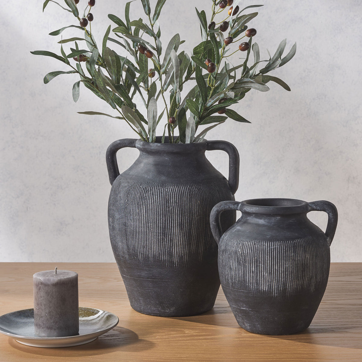 Two charcoal-black vases with loop handles and pale ribbing bring rustic texture to a wood tabletop || RDC1210A-SET2 || front_room
