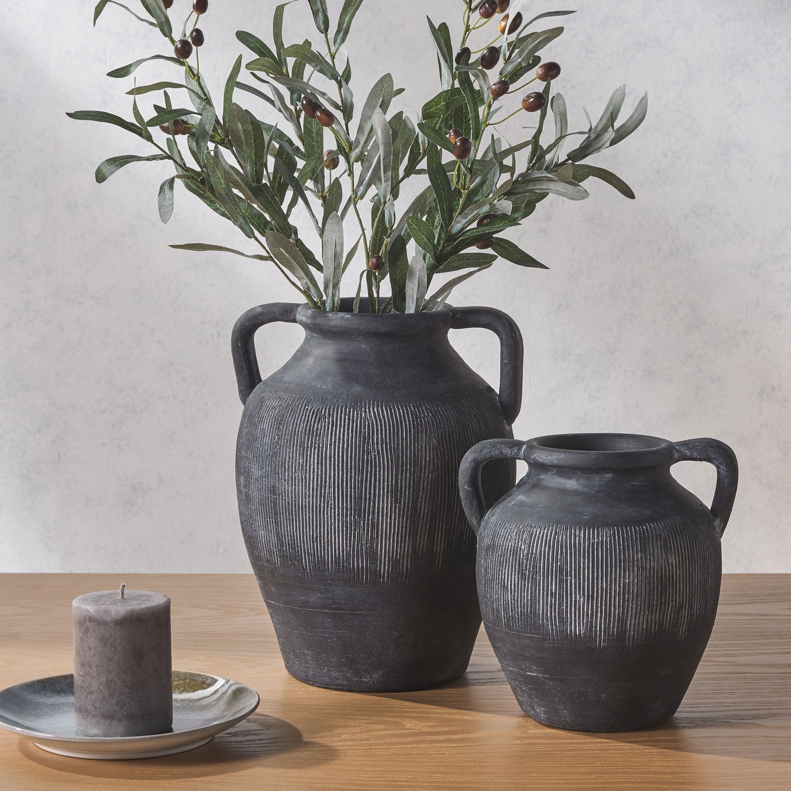 Two charcoal-black vases with loop handles and pale ribbing bring rustic texture to a wood tabletop || RDC1210A-SET2 || front_room