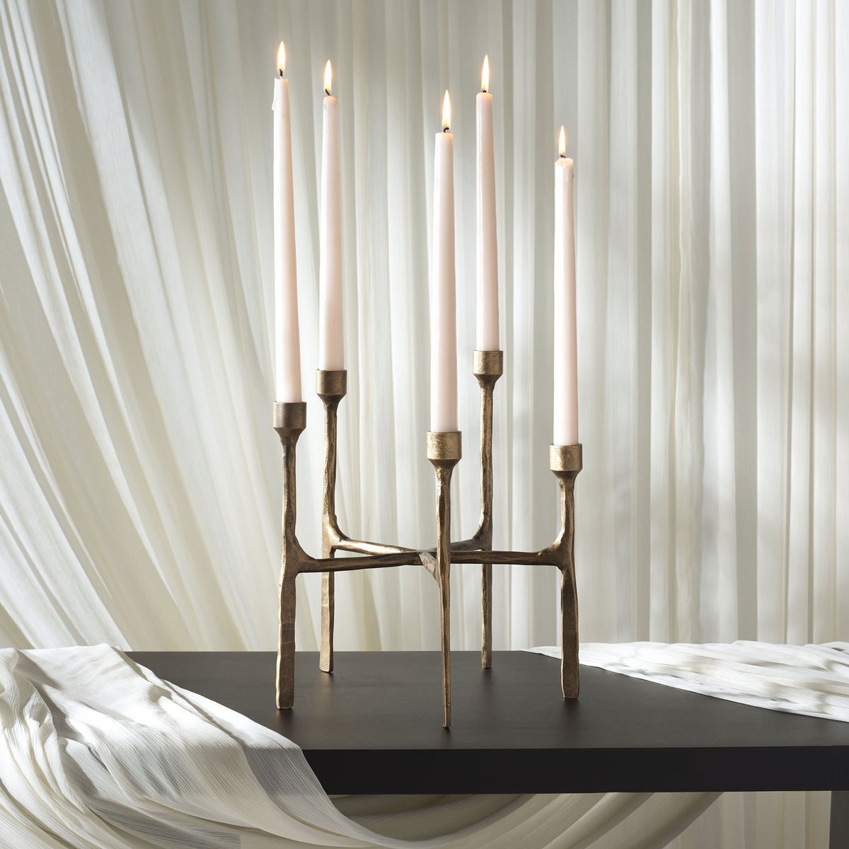 Five lit white tapers lend a warm glow to the sculptural brass-finished centerpiece. || RDC2503A || front_room