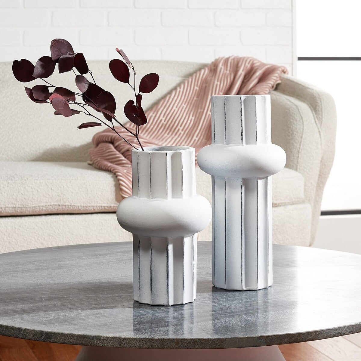 Burgundy foliage lends contrast to the smaller antique white vase beside its taller, fluted companion.
