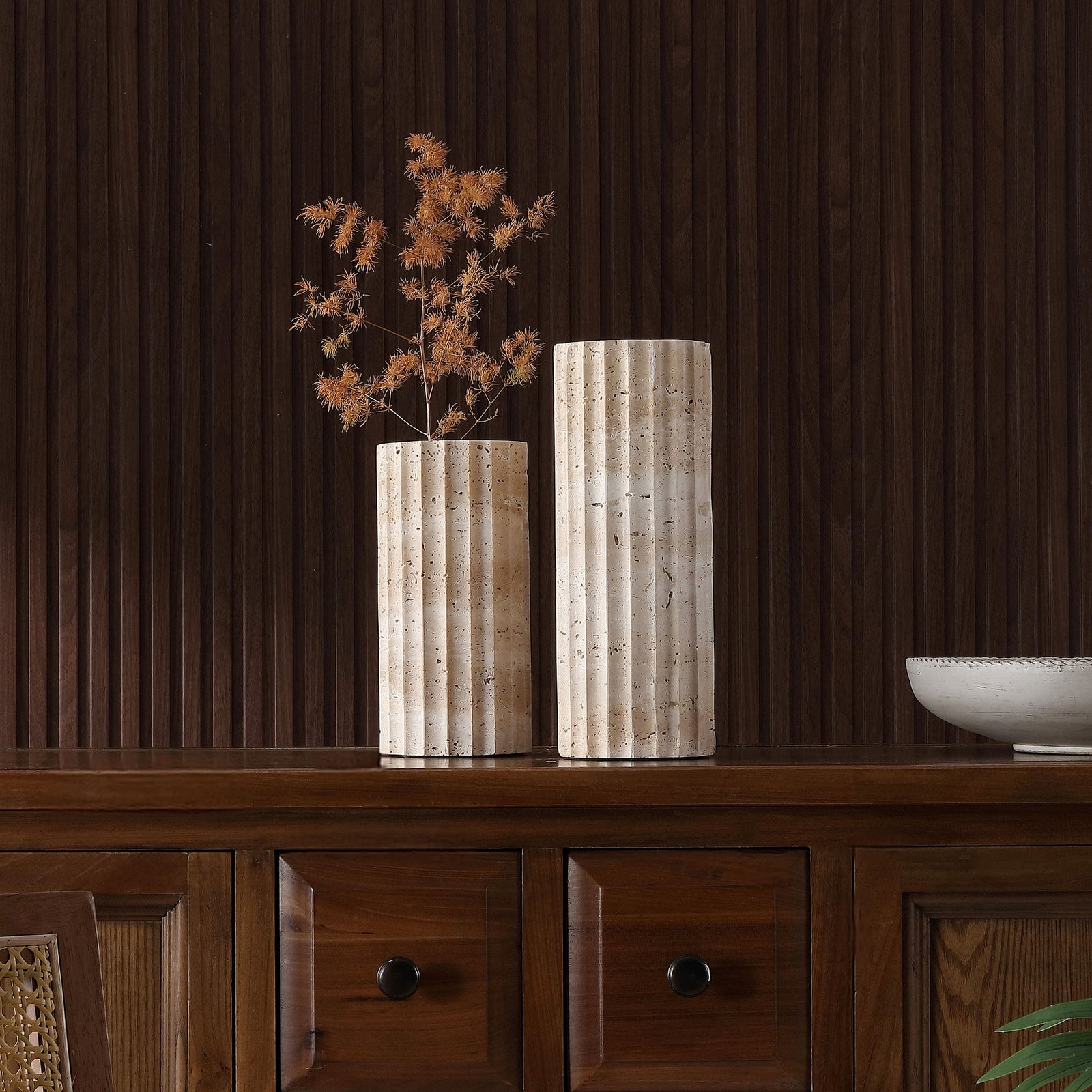 Dried stems fill the shorter vase, highlighting the pair's contrasting heights and textured travertine. || RDC4023A-SET2 || front_room