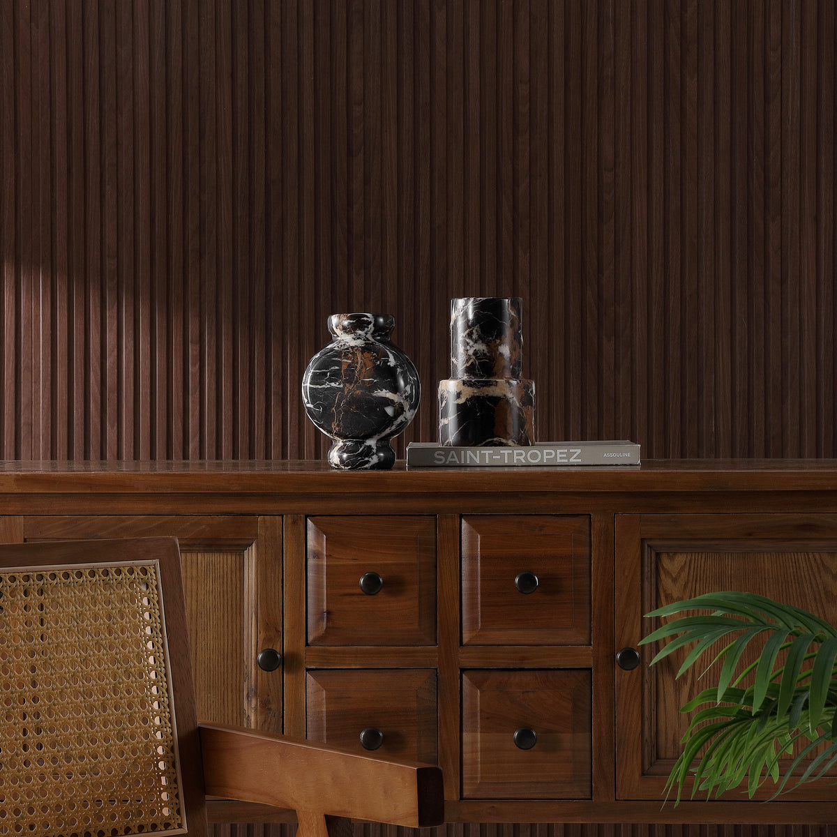 Two black marble vases add sculptural contrast and natural veining to a richly grained wood console